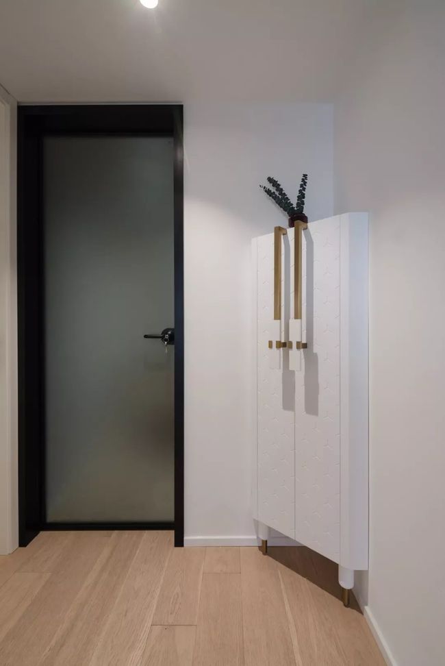 玄关处，设计师利用拐角位置设计了玄关柜，不仅增加了空间收纳，也利用了鸡肋角落。
