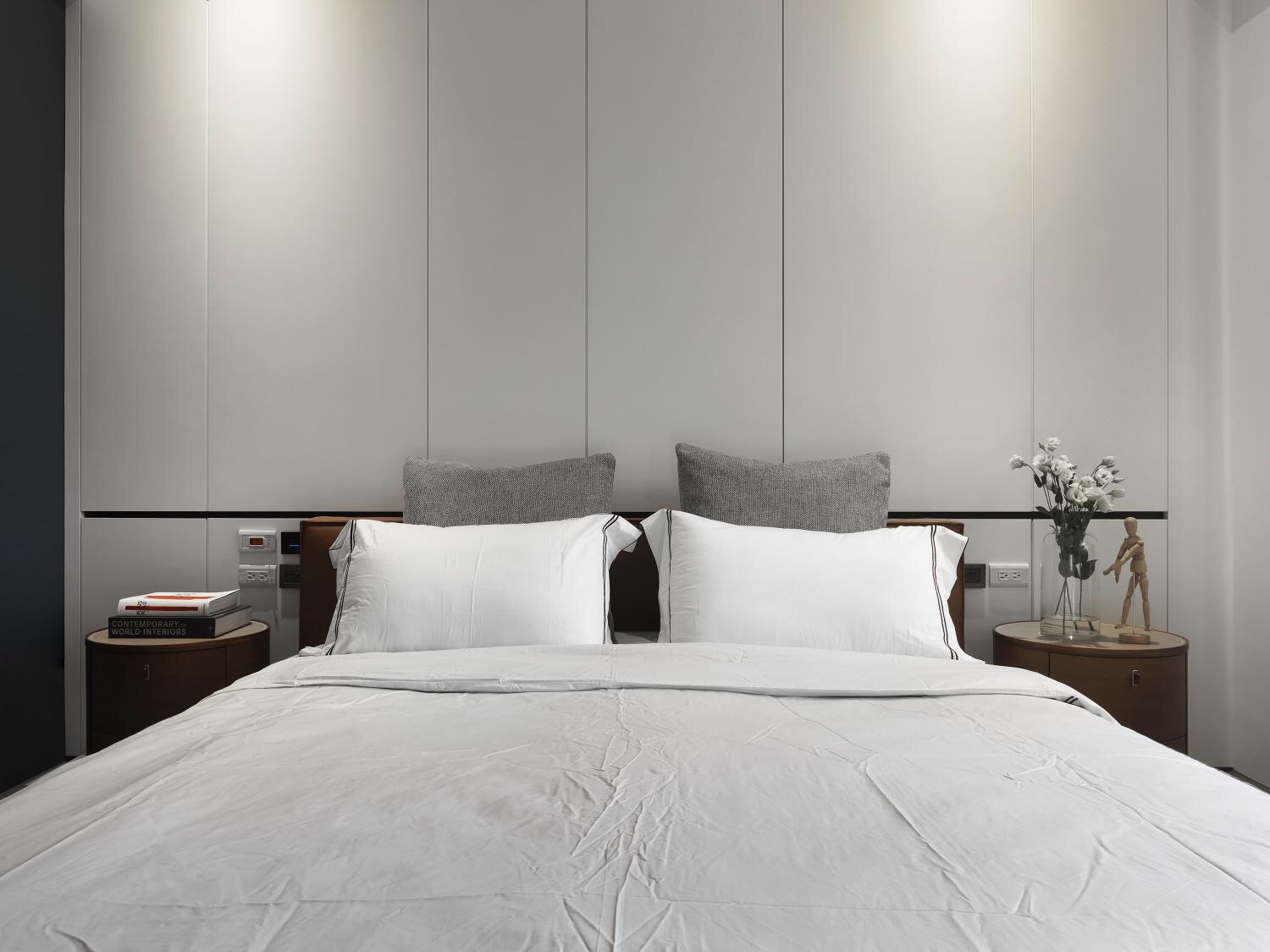 顶面筒灯的烘托下，背景温馨简洁，白色与灰色床品设计提升了卧室的艺术感。