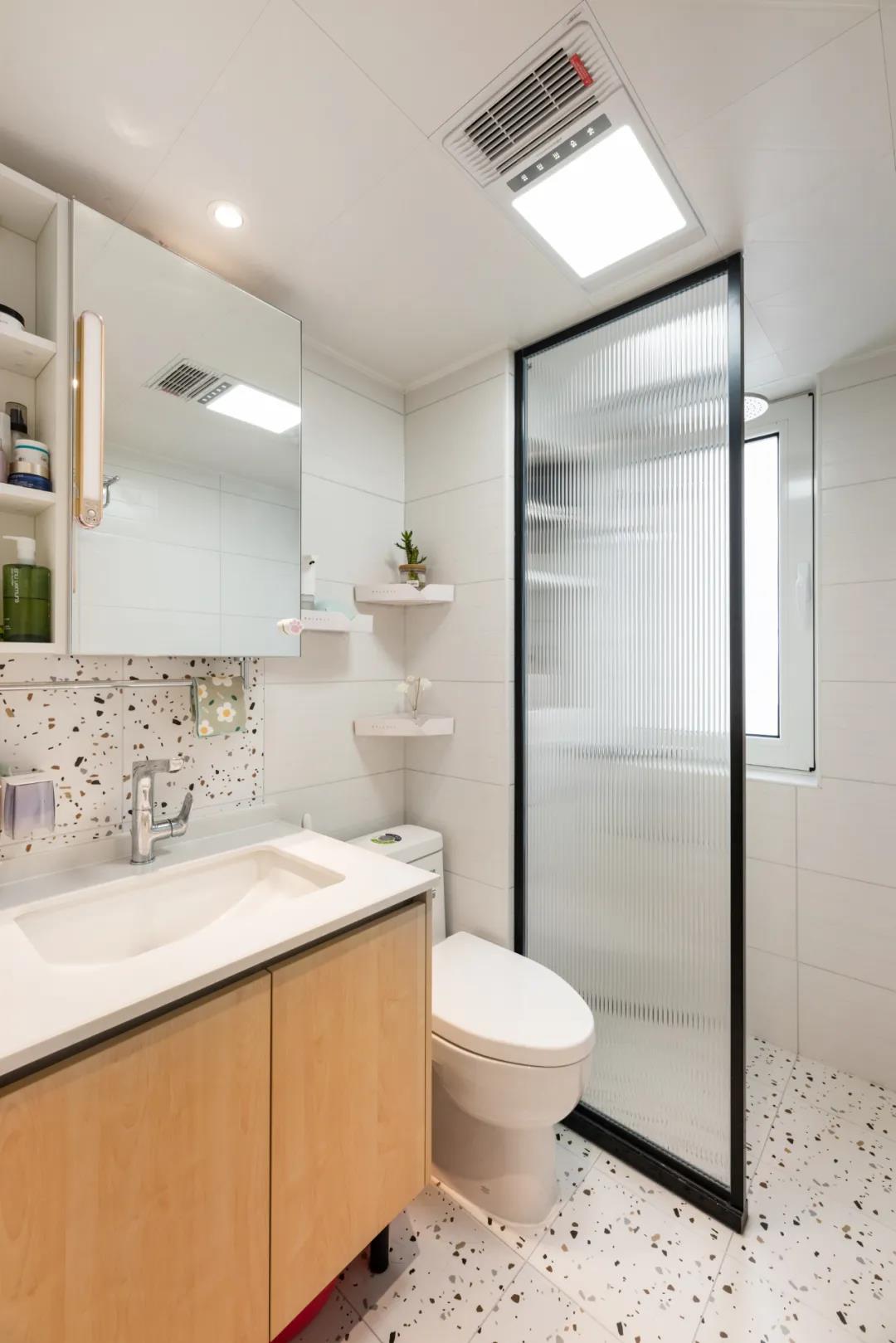 卫生间以白色墙面和地面砖为主，中部使用玻璃做了干湿分离设计。