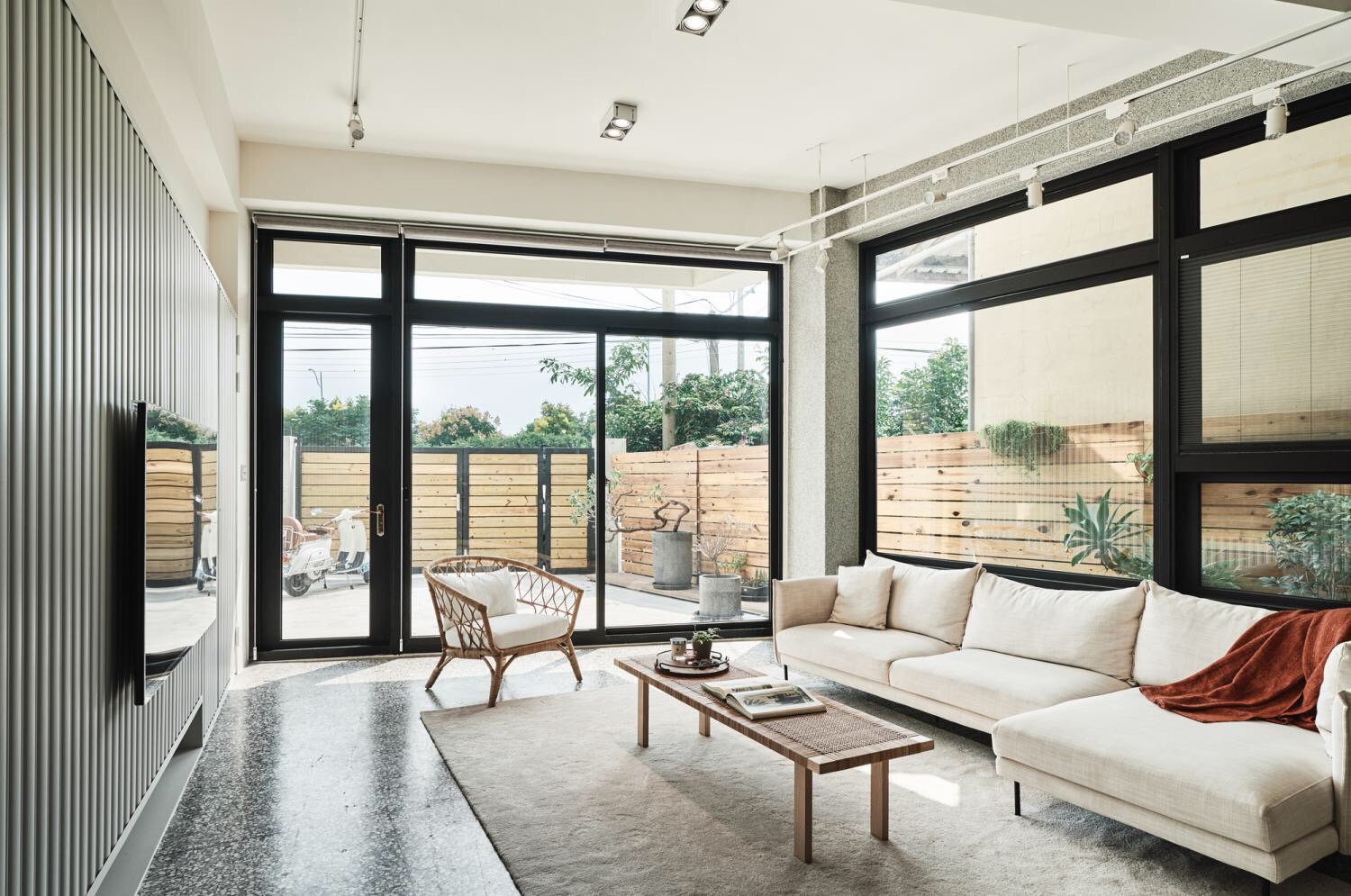 客厅双面落地窗设计，采光较好，白色布艺沙发搭配木质茶几塑造出日系空间感。