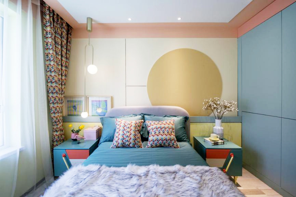 卧室色泽明亮，背景墙配色丰富，搭配蓝色床单，营造出活跃精致的休息区域。