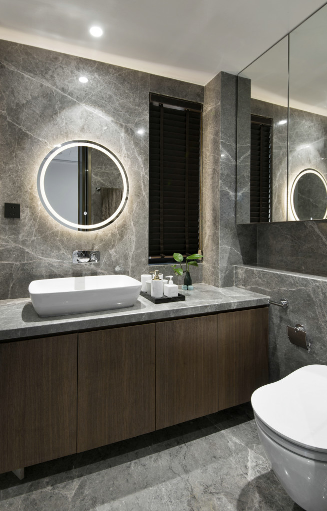 灰色空间带来静谧感，这套卫生间面积不大，洗手台镜面暗藏灯带，成为设计亮点。