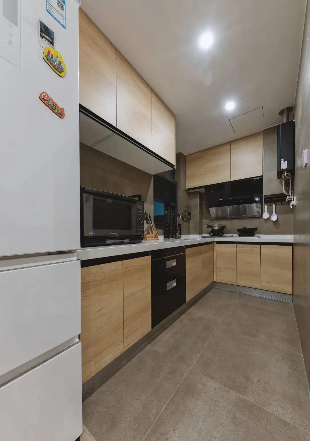 L型厨房休闲大气，木色橱柜搭配白色工作台温暖明亮，厨房动线设计合理。