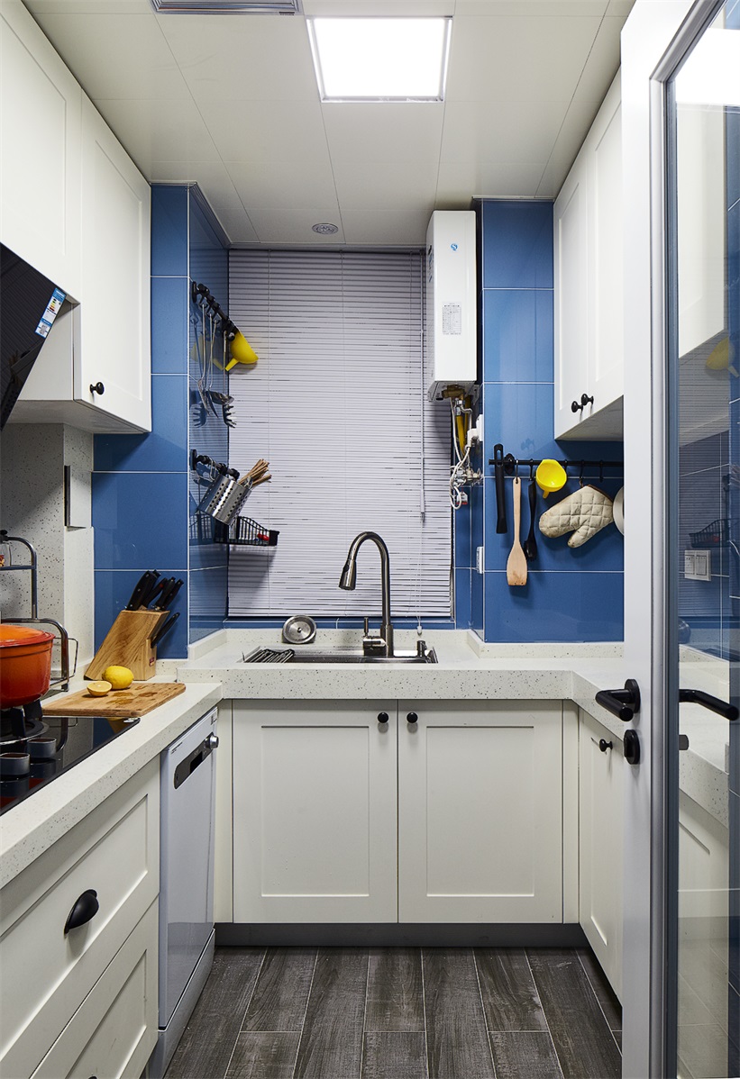 U型厨房设计以白色为主题，色感温和，局部使用蓝色瓷砖点缀，加强了纵深感。