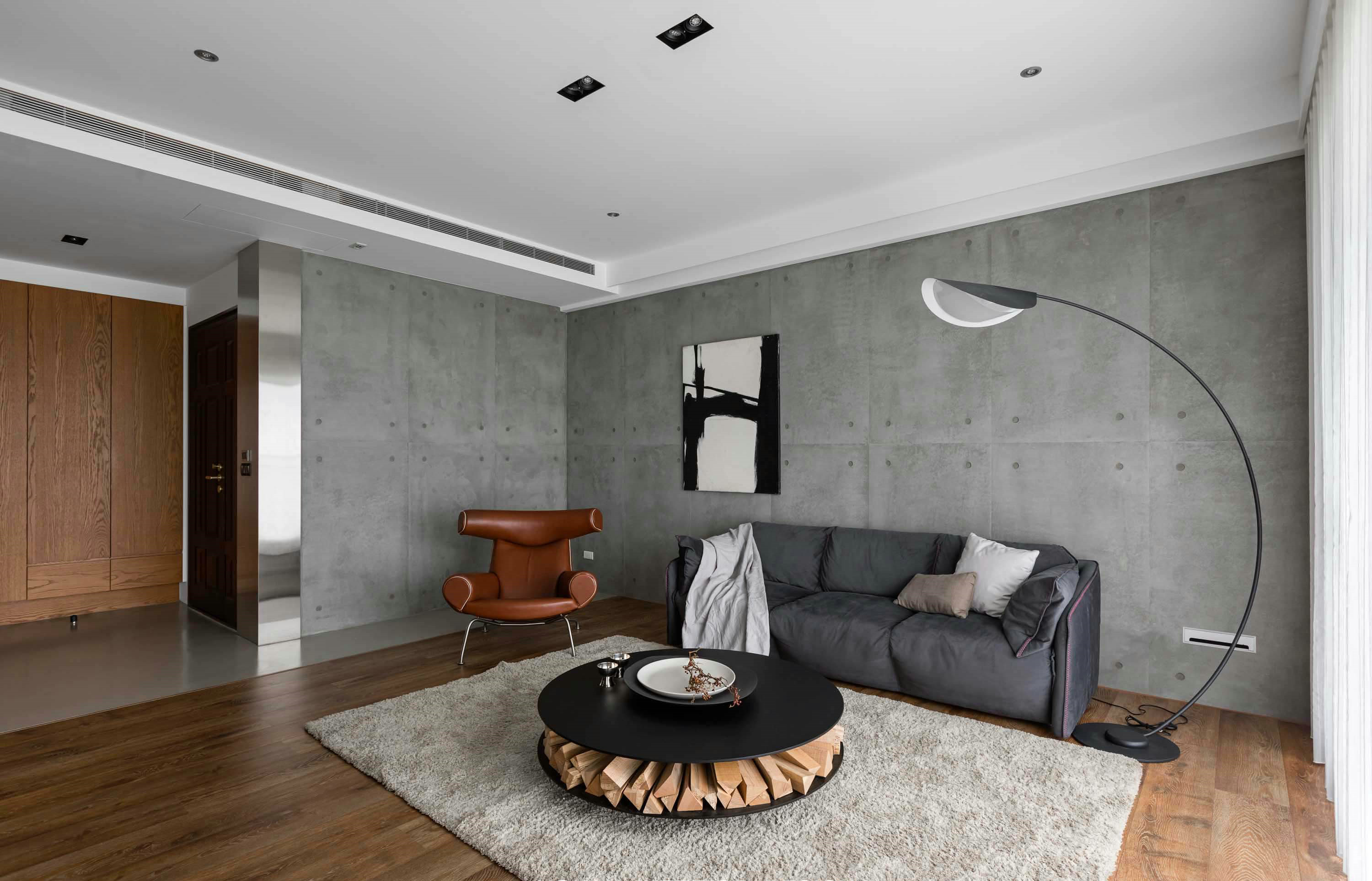 客厅背景墙加入了水泥灰的质感搭配灰色沙发和线形落地灯，空间静谧有大气。