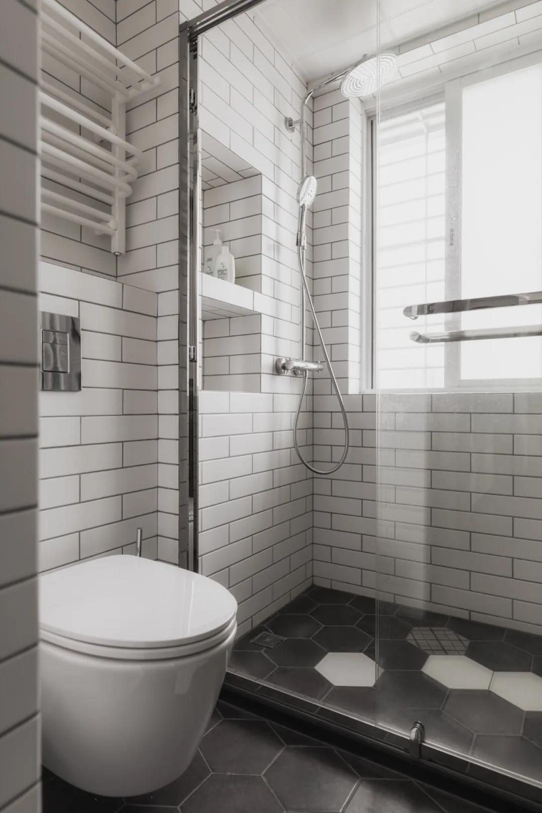 卫浴间以白色为主基调，卫浴房采用玻璃进行干湿分离，墙壁上设计壁龛，增强了收纳能力。