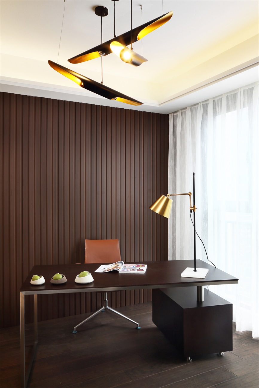 书房的木质背景营造出一个质朴简约的空间，局部金属软装点缀，搭配吊灯烘托，使空间更具格调。 