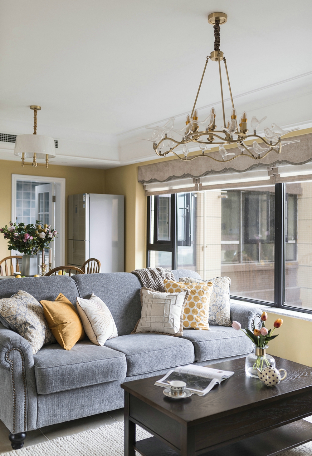 客厅与餐厅相连，通过黄白背景墙烘托静谧背景，搭配丝绒沙发，低调的奢华感油然而生。