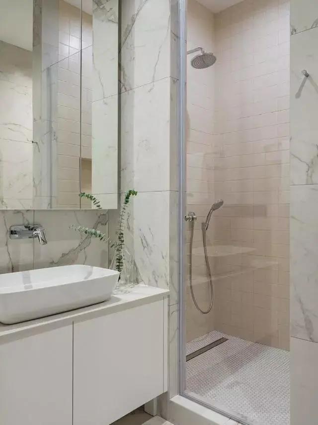 卫生间以白色为背景，定制洗手盆柜组合，采用玻璃进行干湿分离，提供了简约优雅的卫浴体验。