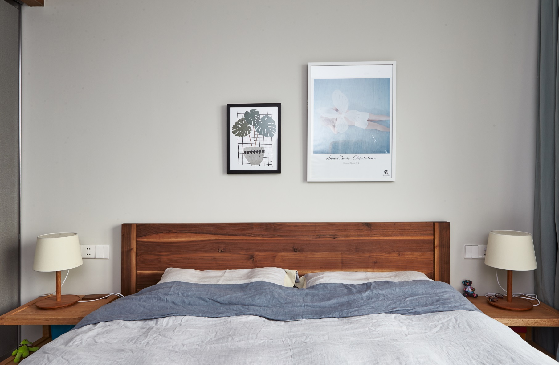 卧室设计简单，原木床头搭配浅色背景墙，呈现出温润雅致的视觉感。
