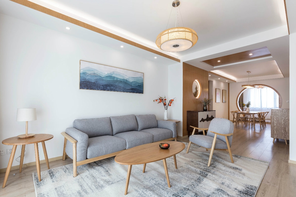 客厅空间以白色为主，灰色沙发搭配木质家具，营造出日系风格的温润内涵。