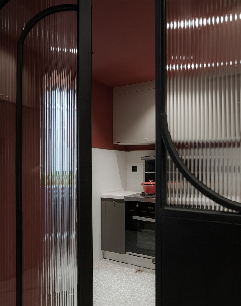 透明的玻璃门设计体现出了厨房空间的时尚感，白色橱柜与橘红色立面相互融合，令空间浪漫而精致。