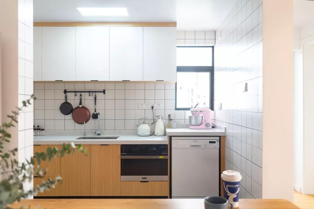 厨房简洁平整，木质橱柜搭配白色吊柜，轻松营造高级质感，凸显出北欧气质。