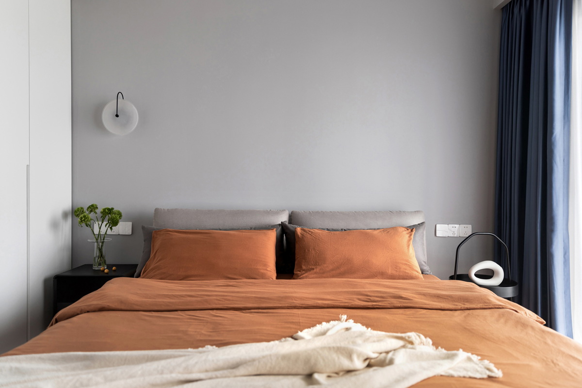 主卧设计低调内敛，橘色床品元素与灰色床头相互融合，整个空间散发出典雅而舒适的气息。