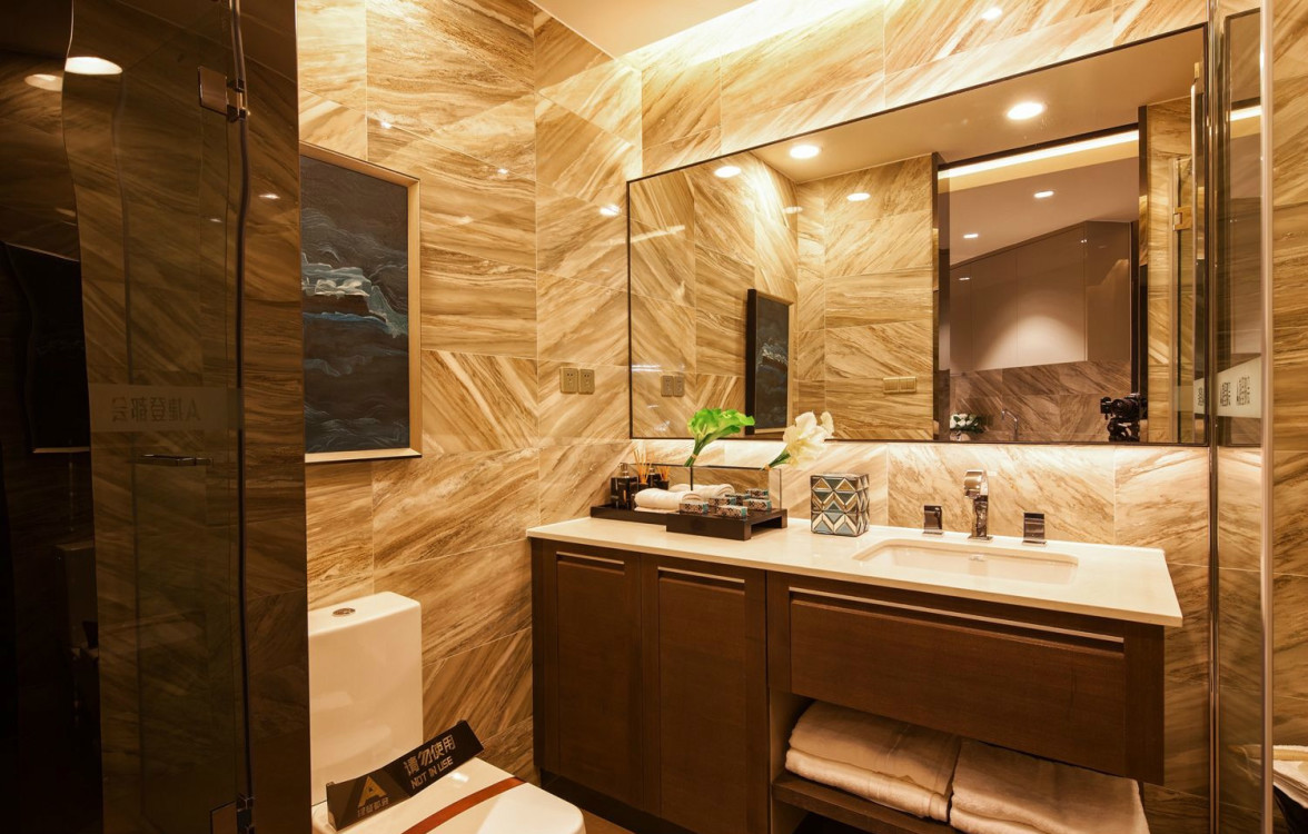 卫浴空间以香槟色为主，顶面筒灯倾泻而下，令米色大理石释放光彩。