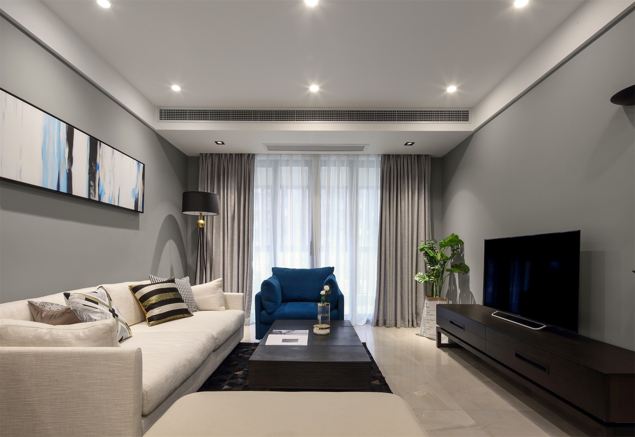 浅白色的沙发轻奢时尚，亮色装饰画结合灰色背景墙，营造出一个特色鲜明的客厅空间。