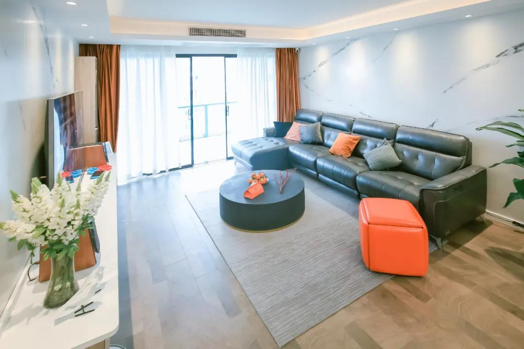 客厅整体以现代风格为基调，皮质沙发搭配白色大理石背景墙，带来一种简约舒适的氛围。