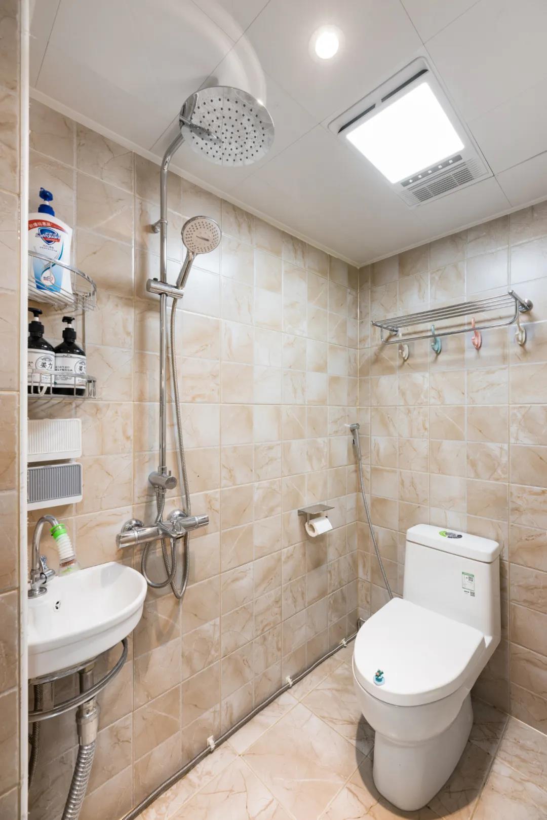 卫生间以米色瓷砖为背景，白色洁具在整个空间显得简约从容而舒适。