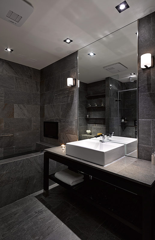 深灰色背景墙使卫生间高级感十足，洗手区域加入大尺寸镜子，提高了室内的光线感。