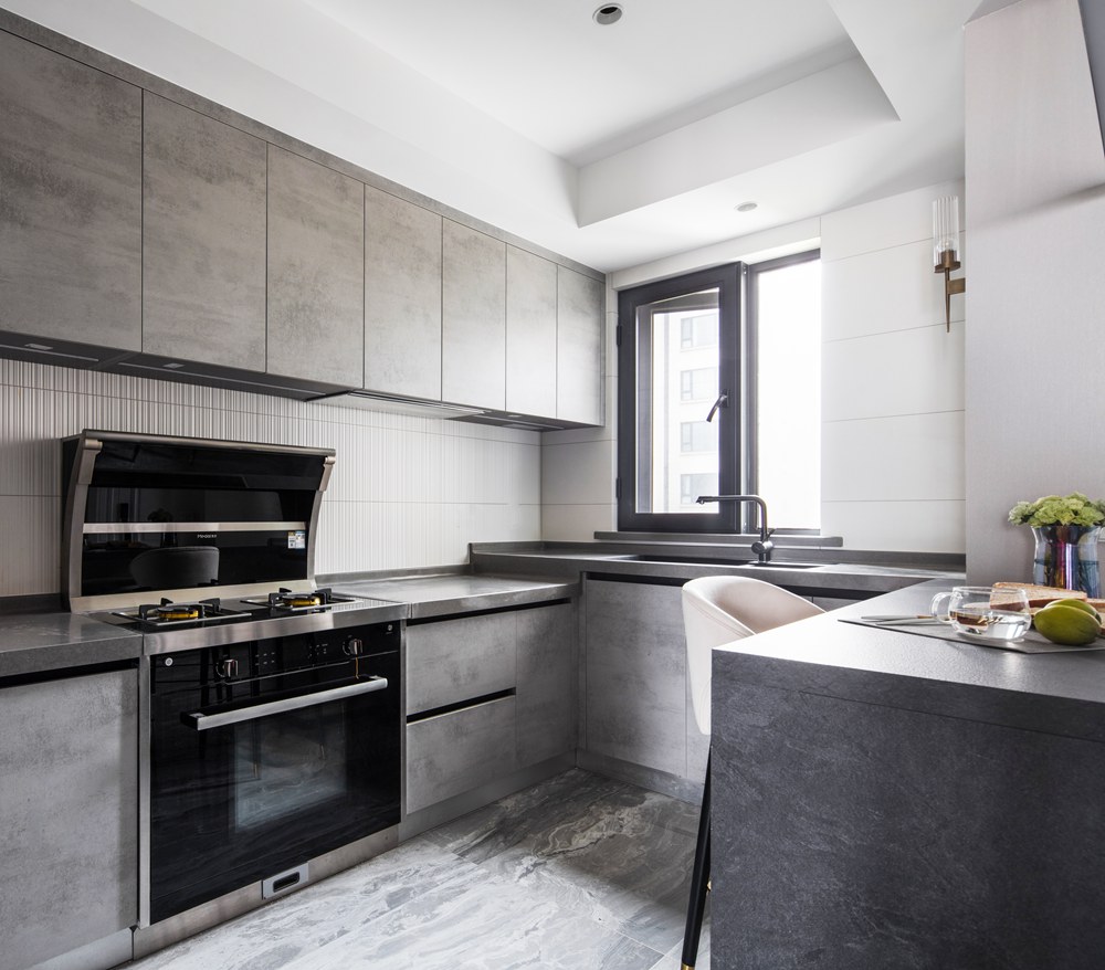 厨房采用“U”型的布局设计，米灰色橱柜硬朗利落，营造出大气静谧的厨房空间。