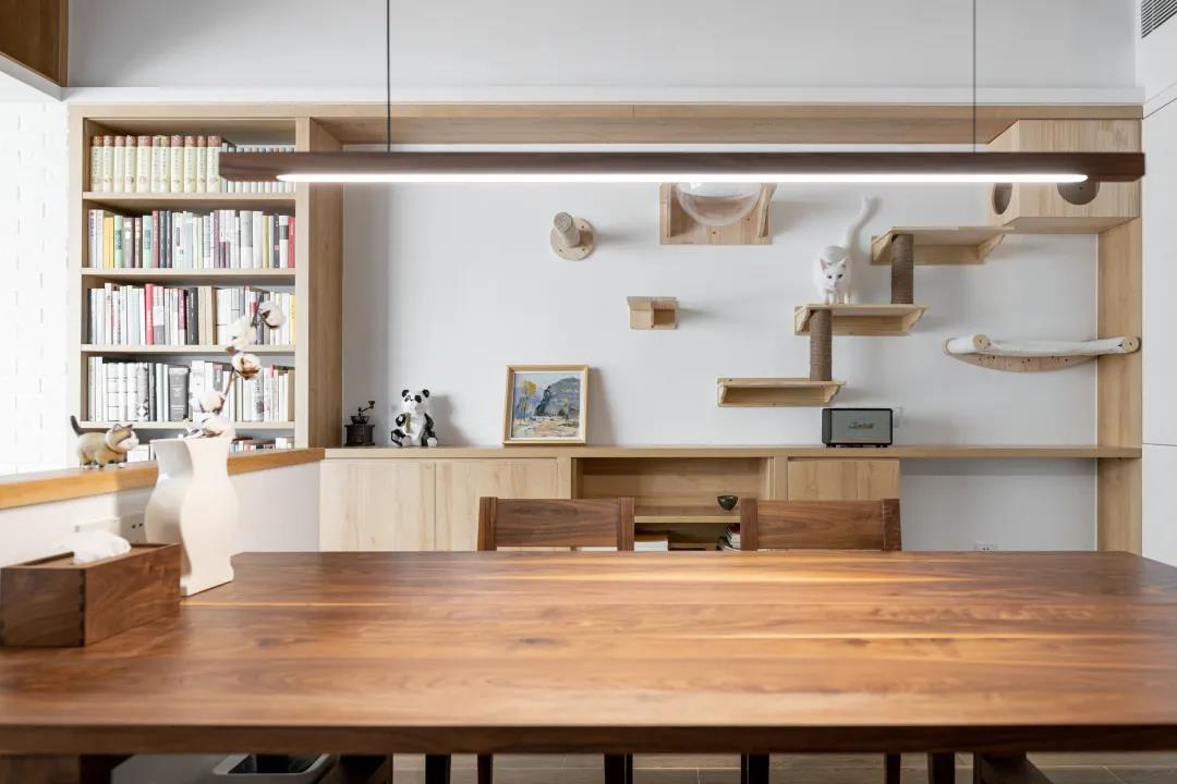 餐桌使用实木材质打造，配合背景墙猫架，让整体空间舒适不失优雅温润。
