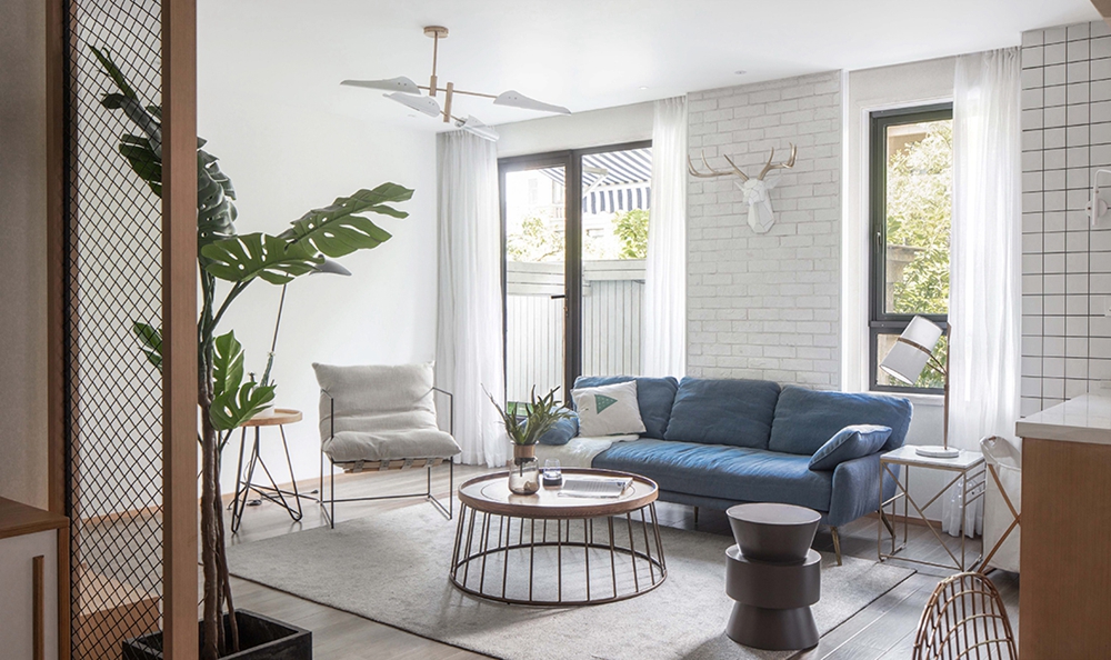 客厅背景为白色，搭配蓝色沙发和绿植，创造出一个舒缓放松的视觉环境。