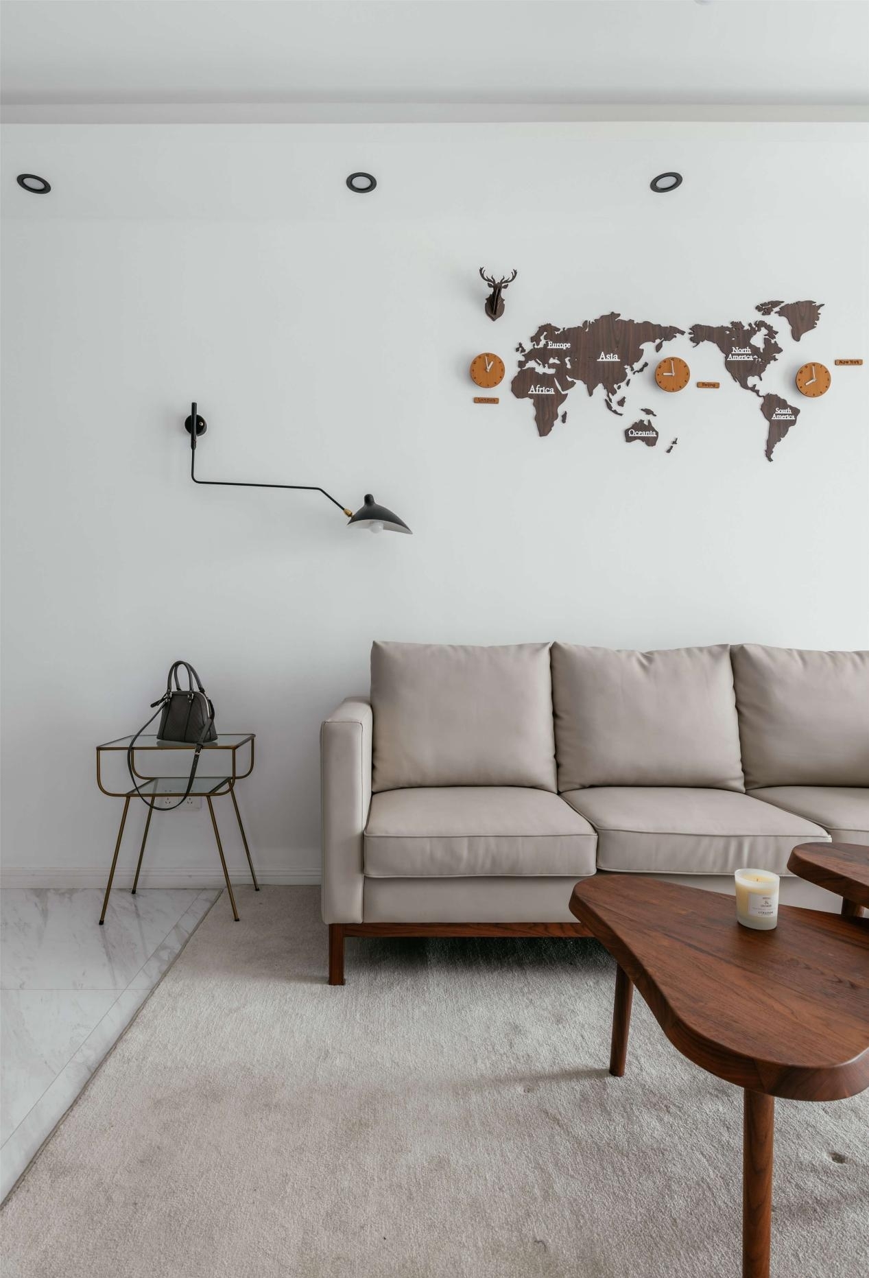 米白色的皮革沙发颜色更加柔和，简单高级。墙面上是一幅平面的世界地图，实木材质更具质感。