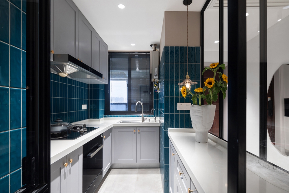 厨房设计繁而不杂，橱柜以浅色打造，背景铺贴蓝色砖面，细节处尽现优雅。