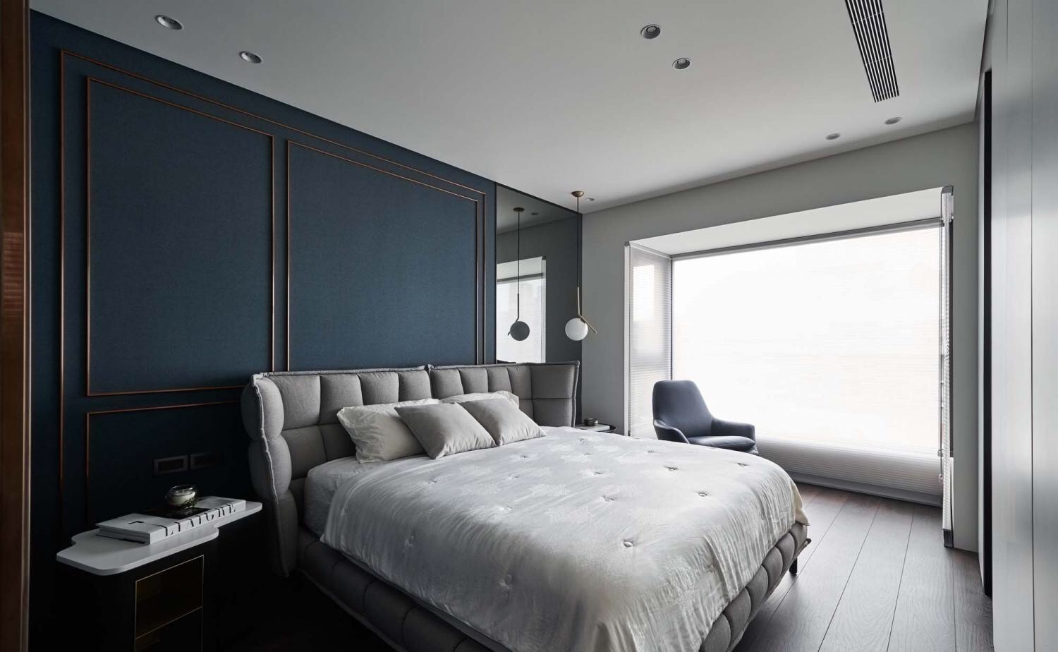 蓝色背景墙增加了空间的体量感，灰色床头搭配垂吊灯具，轻松俘获人心。