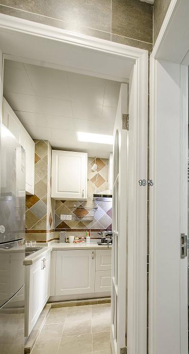 厨房设计简约自然，白色橱柜沉浸在米色花砖的空间氛围中，传递出质朴之美。