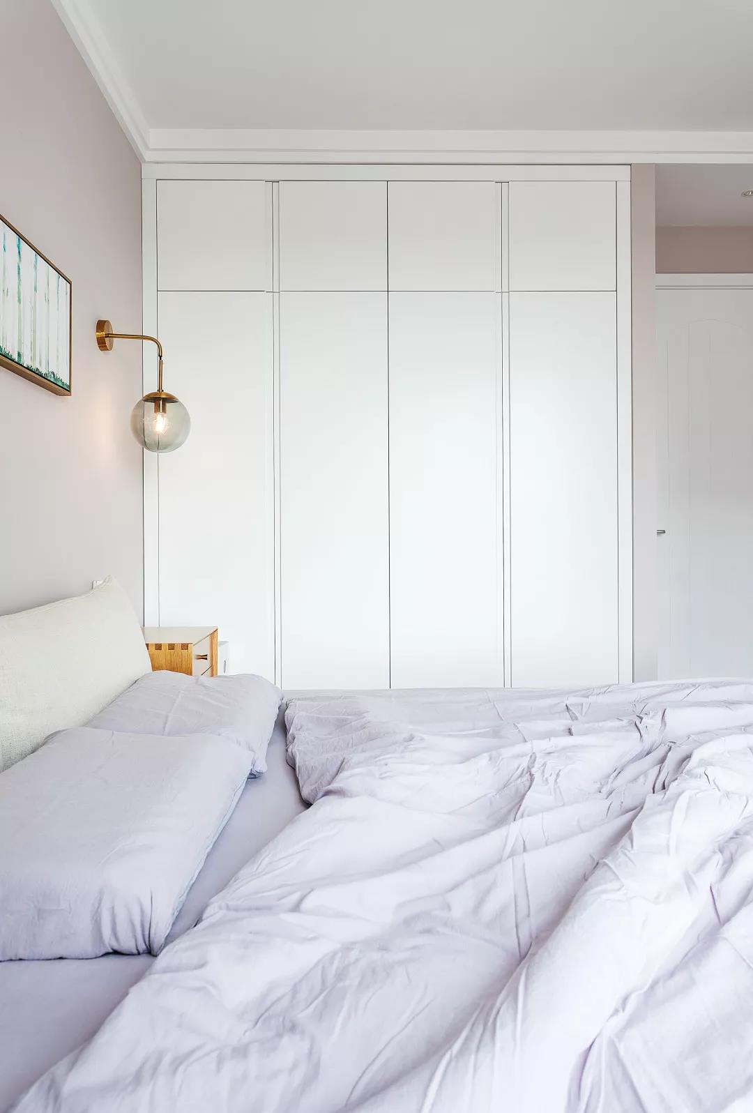 紫白的软装布置，在自然舒适的灯光下，白色嵌入式衣柜带来一种精致的卧室生活氛围。