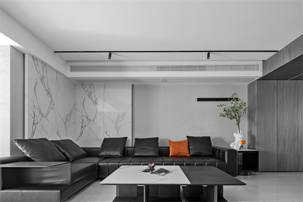 黑色皮质沙发搭配灰色背景墙理性沉稳,局部橘色抱枕点缀,提升时尚感