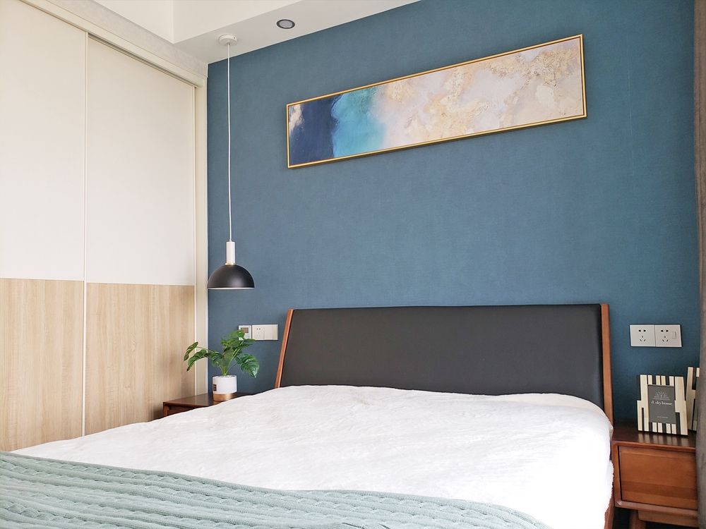 蓝色背景墙设计简单，虽然大面积留白，但并没有感觉到枯燥，搭配装饰画和绿植，反而多了些许的意境。