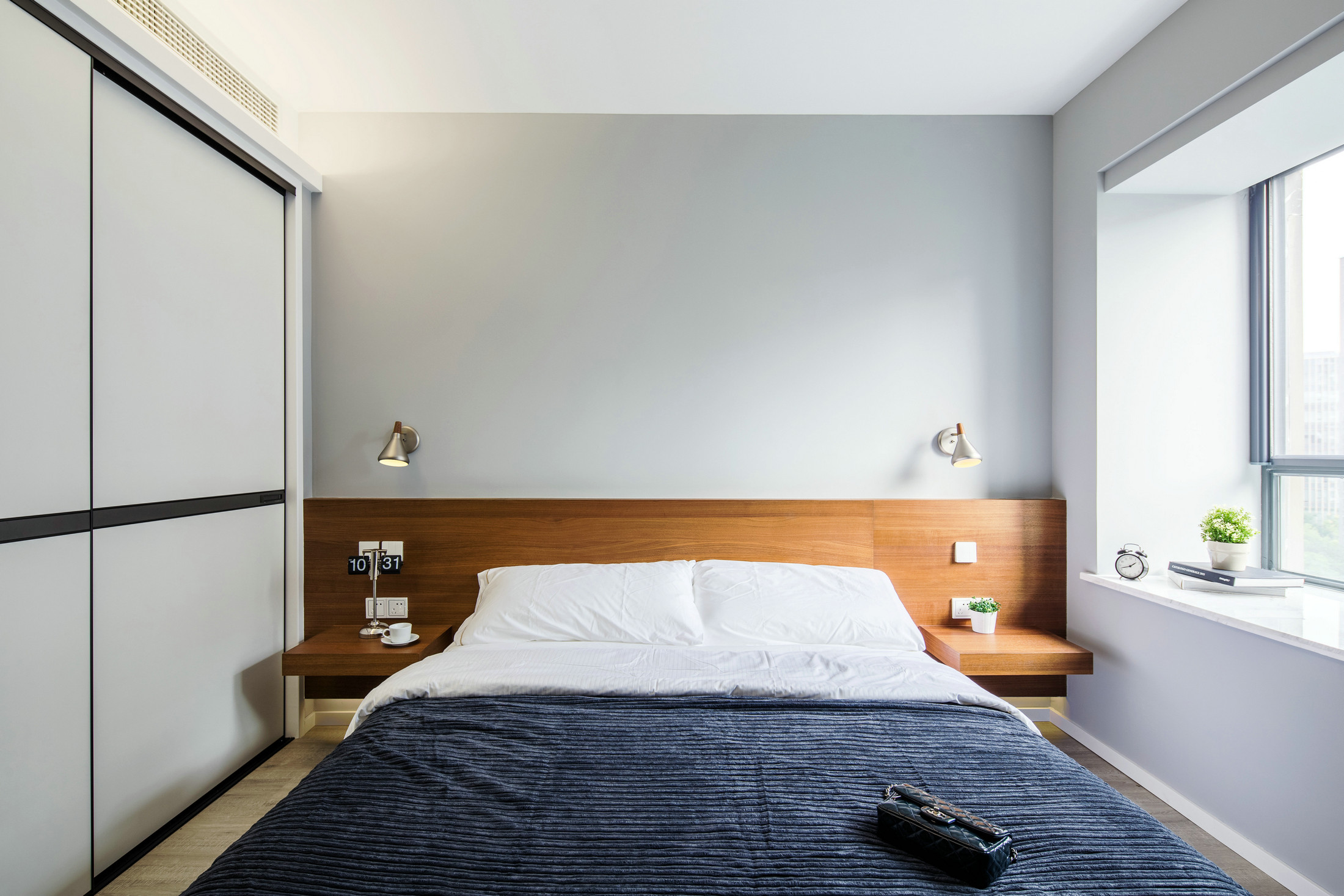 次卧背景墙删繁就简，木质调的融入令空间显得更加柔和，蓝色床品提升了一丝庄严感。