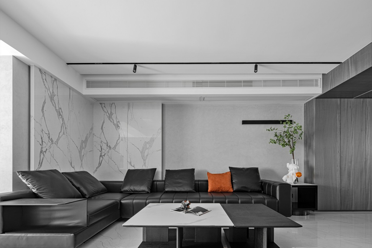 客厅低调中彰显着不凡的气质，黑色皮质沙发中放置橘色抱枕，提升了空间色感。