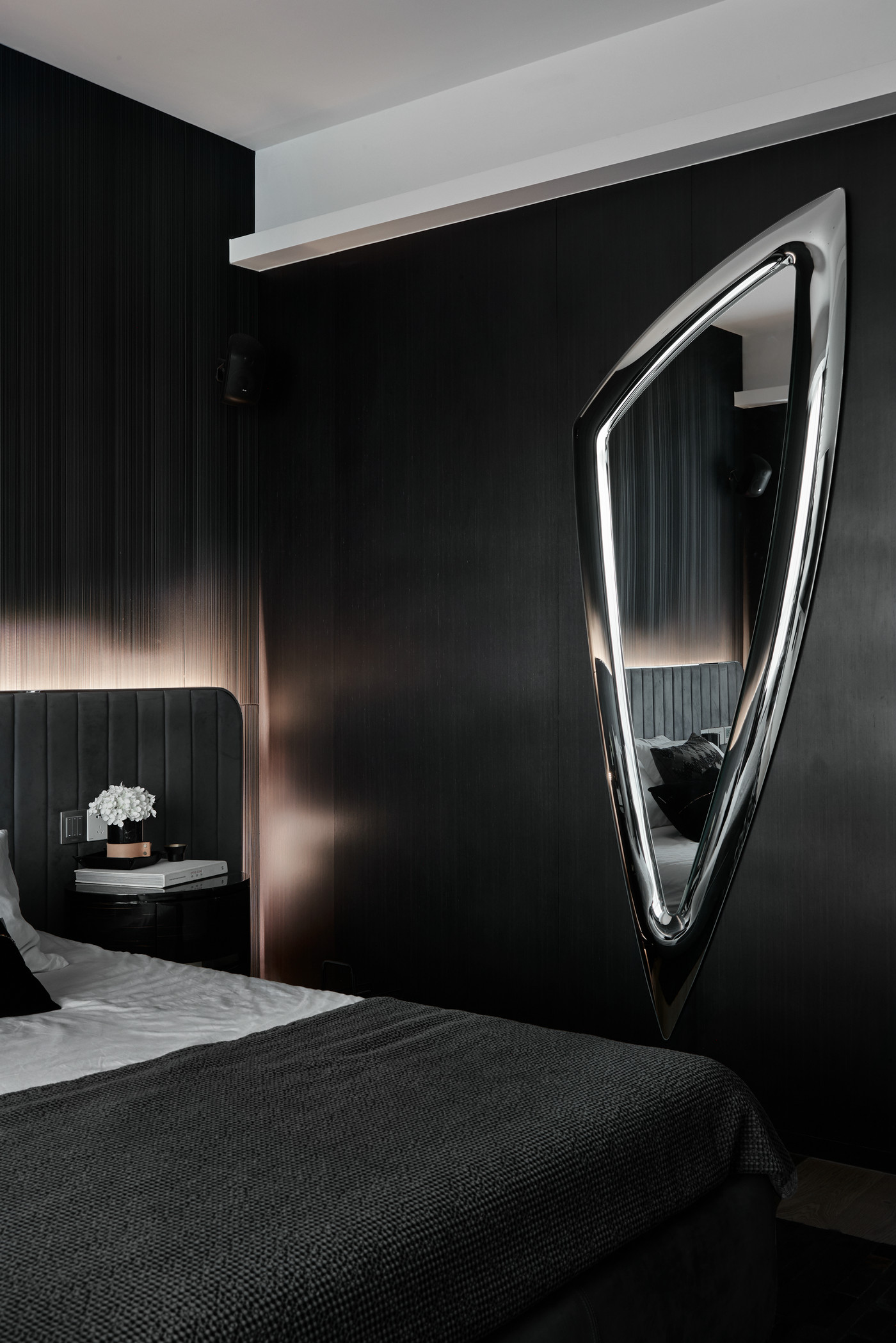 卧室全黑设计形成静谧的睡眠空间，背景墙一抹镜面，为空间灌入活力。