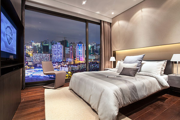米色调的次卧空间，背景墙层次感强，搭配灰白色床品，卧室显得静谧而舒适。