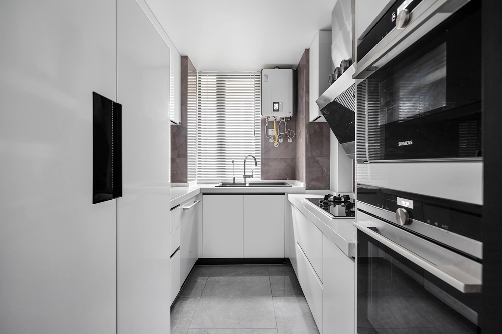 厨房白用黑白格调，白色橱柜配以黑色电器，营造出舒适的现代烹饪环境。