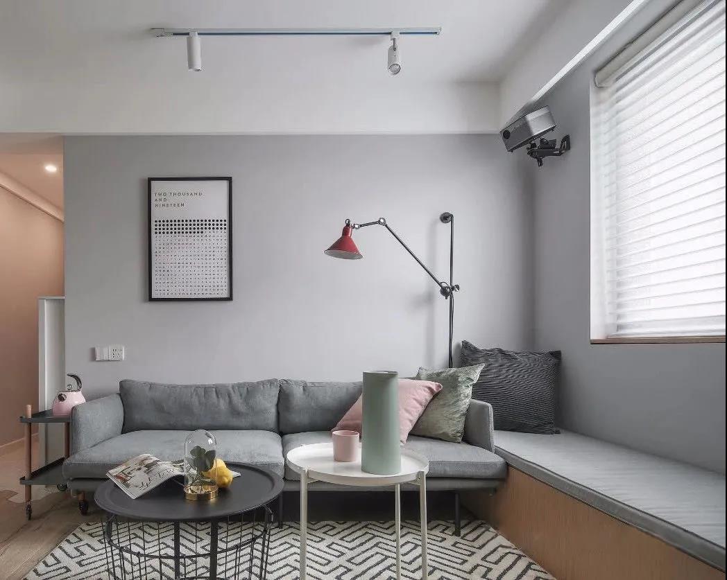 灰色布艺沙发与灰色背景墙搭配，配合光影与飘窗，组合成一幅北欧风图景。