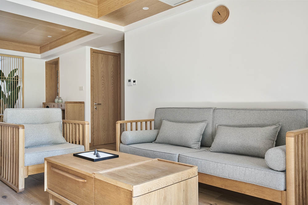 白色的墙面背景，搭配灰色沙发设计，时尚简约，木质元素的融入，令空间含蓄温馨。