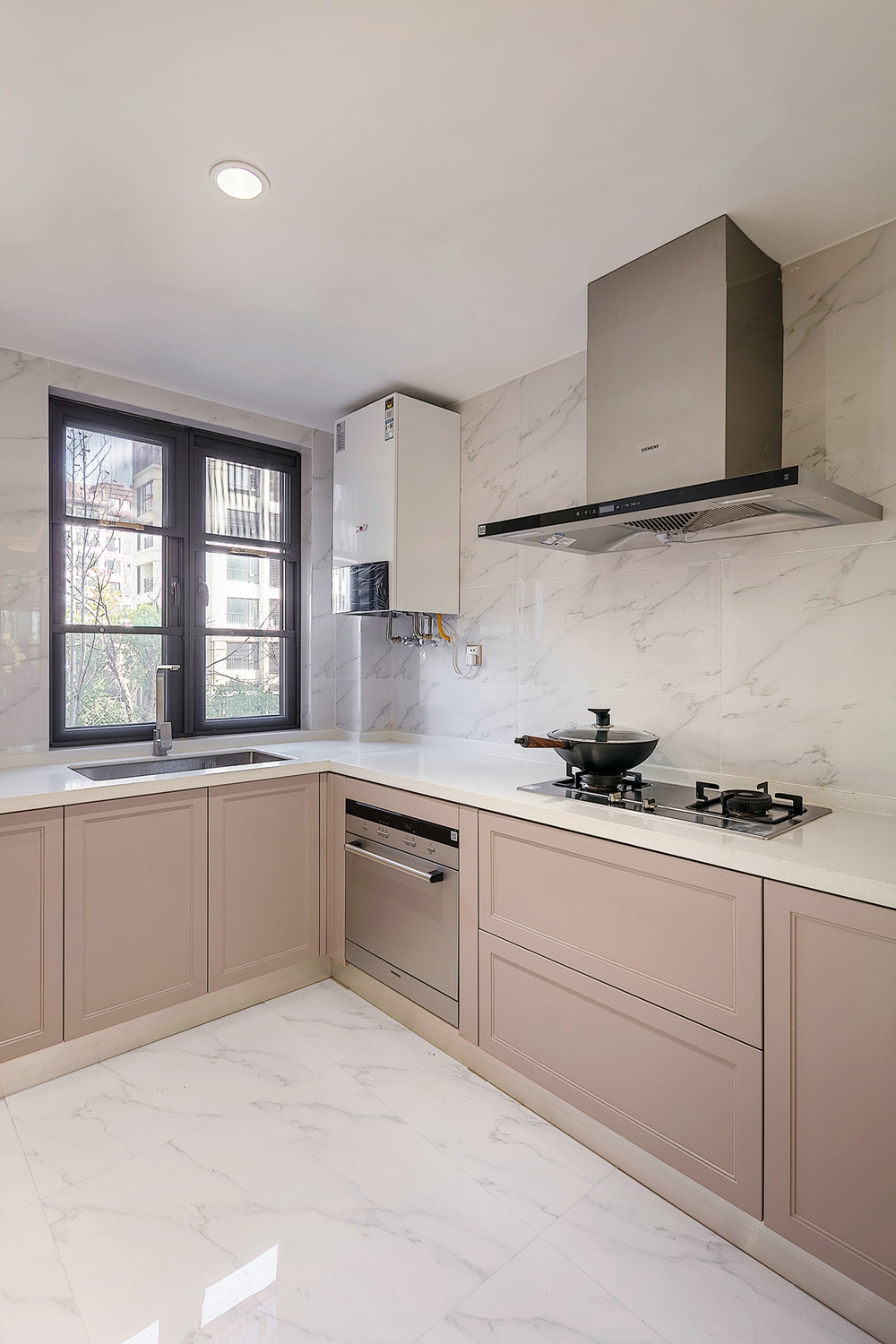 粉色橱柜构成厨房一幅和谐的画面，在白色大理石背景下体现出空间的轻奢质感。
