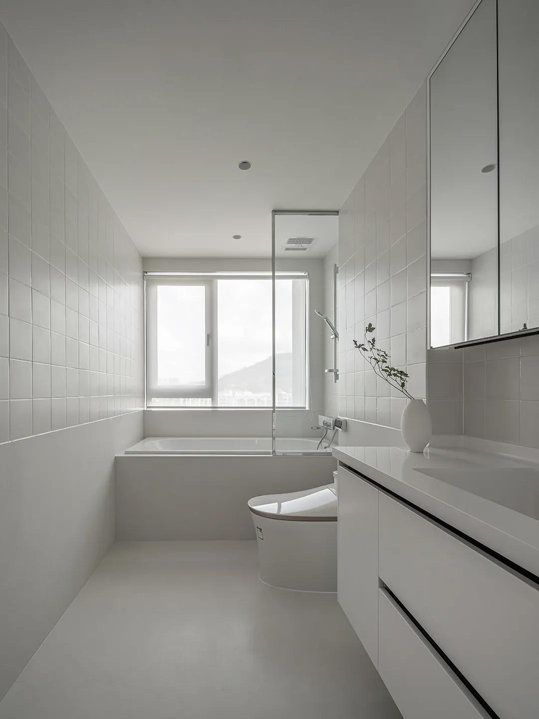 卫浴空间以白色调为主题，视觉效果明亮简洁，浴缸一侧采用玻璃进行干湿分离。