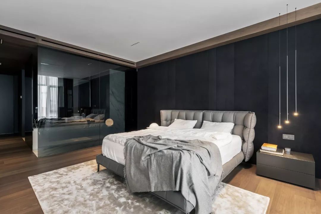主卧面积宽敞，背景墙以黑色为基调，整体的色彩搭配和谐美观，床头灯具氛围感强。