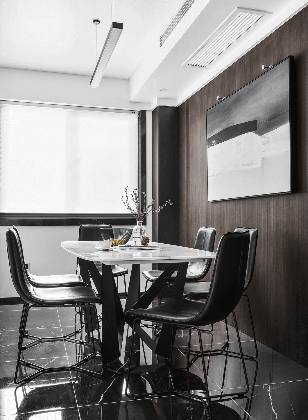 餐厅背景墙选用了深咖色木饰面，并选择了一幅黑色系的抽象画，白色的大理石桌面与客厅的茶几相呼应。
