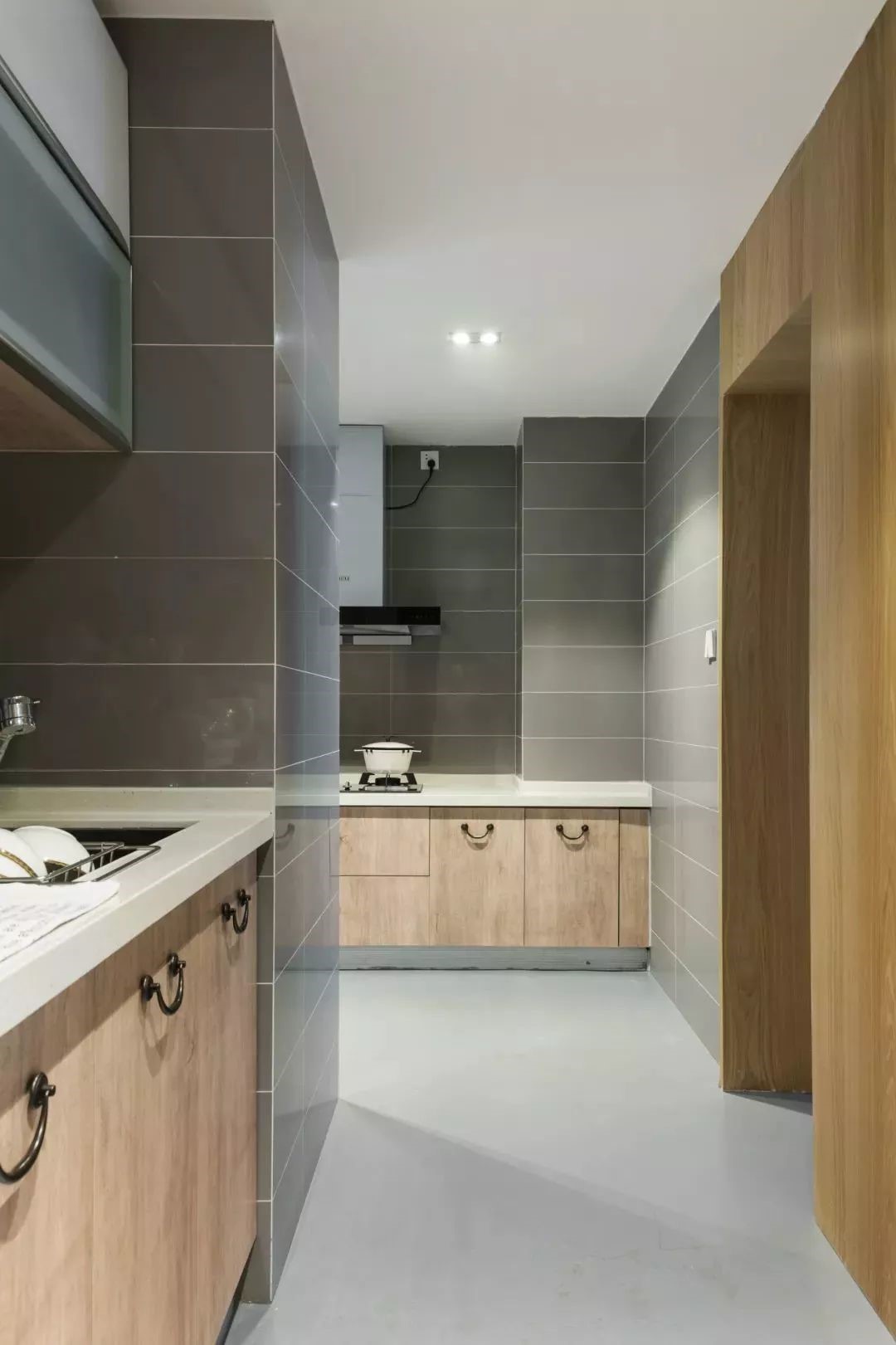 厨房的烹饪区墙面以灰色砖与地面，搭配木质感的橱柜，整体显得格外的优雅时尚。