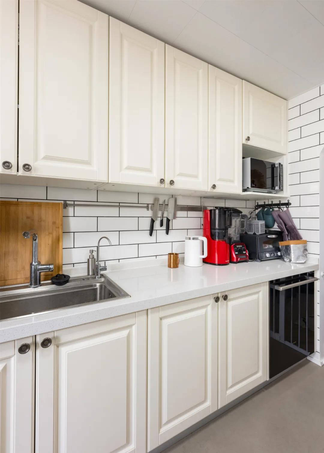 厨房空间以白色为主，简洁大气，背景砖块营造出清新明亮的氛围。