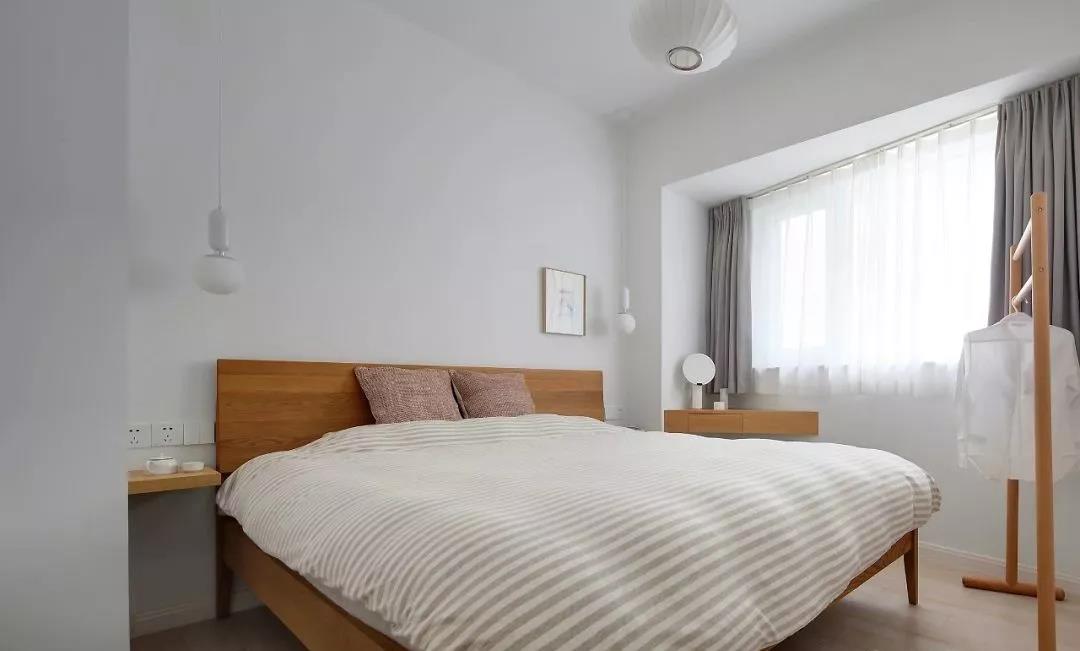 净色背景墙搭配木色床头，使室内的温润感得以延伸，空间色彩层次丰富而又有现代感。