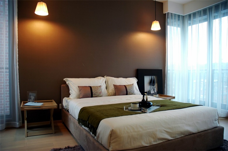 主卧设计多使用冷色调，床头背景墙采用咖色设计，顶层两边是对称式吊灯造型，精致有特色。