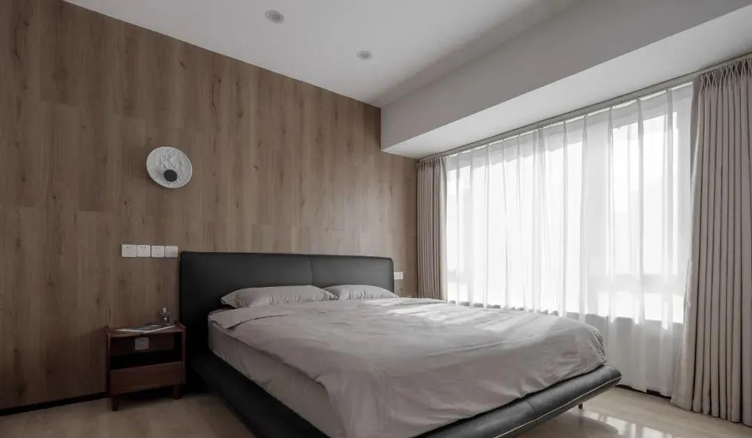 主卧大面积使用木饰面板渲染，黑色床头与白色床品凸显出空间的美式气质。