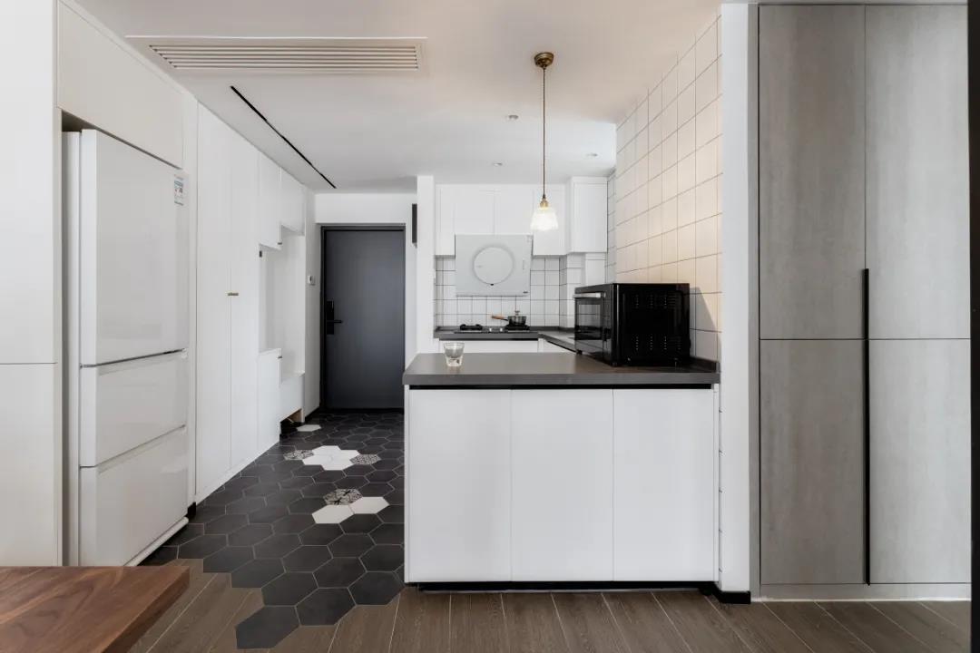 厨房采用了白色做橱柜，深色工作台形成一种对比色，让厨房看上去更加高大上具有品味。